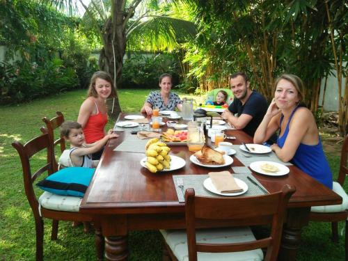 a family sitting around a table eating food at Sisikirana Villa (Luxury Villa in Galle) in Unawatuna