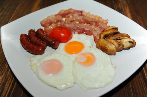 a plate of breakfast food with eggs sausage and mushrooms at Hotel Astoria in Tivat