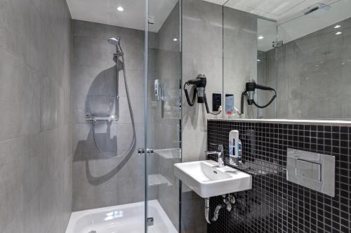 a bathroom with a shower and a sink at MEININGER Hotel Berlin East Side Gallery in Berlin