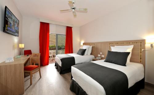 a hotel room with two beds and a desk at Hotel Salobreña Suites in Salobreña