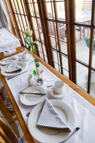 a table with white plates and a vase with a flower at Moncrieff Manor in Knysna