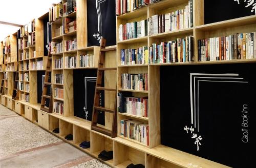
a book shelf filled with books on top of each other at Cao Ji Book Inn Hostel in Tainan
