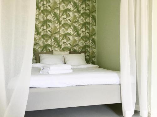 a bed with white sheets and a wallpaper with palm trees at Magnificent sea view! Luminous 1 br for max 4 in Helsinki