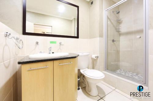 Un baño con inodoro, lavabo y ducha. en Prestige Apartments Sandton at Westpoint, en Johannesburgo
