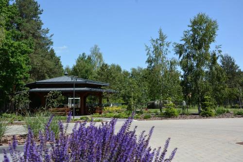 a gazebo in a park with purple flowers at Hotel KARO in Radom