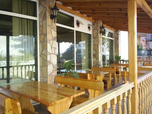 un restaurante con mesas de madera y bancos en un porche en Family Hotel The Rocks en Belogradchik