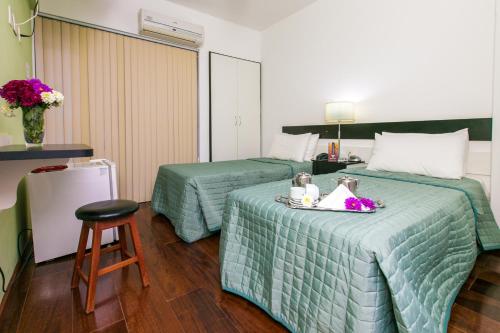 een hotelkamer met 2 bedden en een kruk bij Hotel Minas Tower in Leopoldina