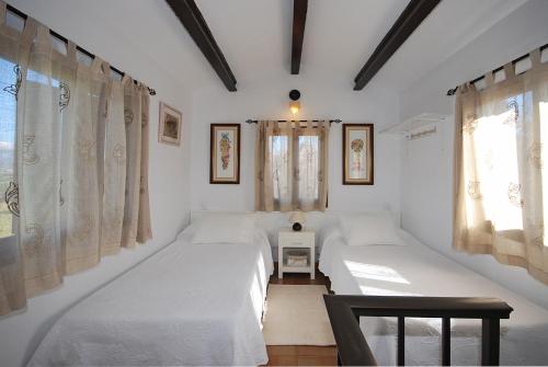 a bedroom with two beds and two windows at Villa Tramuntana in Inca