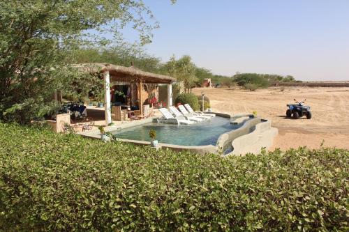 a swimming pool with chairs and a gazebo at Hôtel Les Cordons Bleus in Ndangane