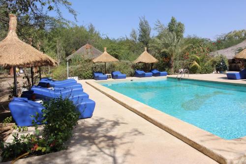 a swimming pool with blue chairs and umbrellas at Hôtel Les Cordons Bleus in Ndangane