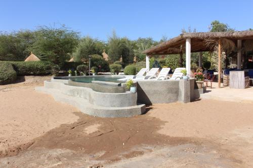 a swimming pool with a bunch of chairs around it at Hôtel Les Cordons Bleus in Ndangane