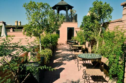 eine Terrasse mit Tischen, Stühlen und einem Pavillon in der Unterkunft Riad ILayka in Marrakesch