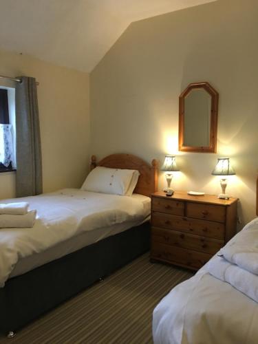 a bedroom with two beds and a dresser and a mirror at Our Snug in Riccall