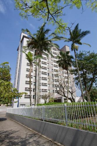 a tall white building with palm trees in front of it at Comfort Hotel Joinville in Joinville