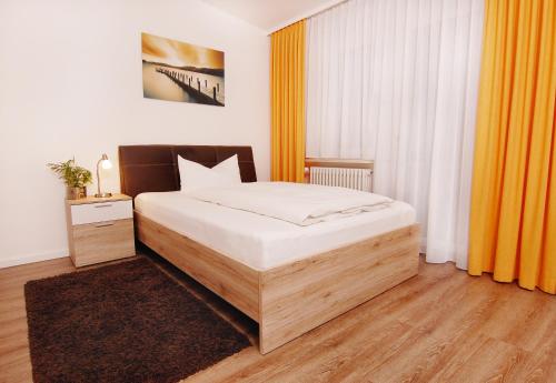 a bedroom with a large bed and orange curtains at Garni Hotel Leitl GmbH in Eggenfelden