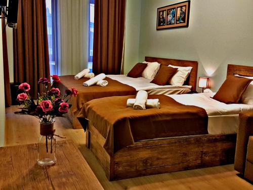 a bedroom with two beds and a vase of flowers at Hotel Holiday Villa in Tbilisi City