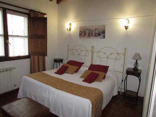 a bedroom with a large white bed with red pillows at Posada rural el rincón de Cabrojo in Cabrojo
