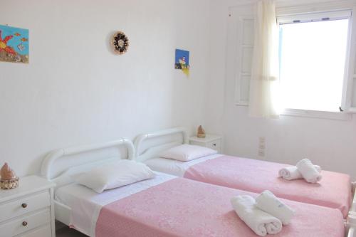 two beds in a bedroom with pink sheets and towels at Remvi Studios in Pounda