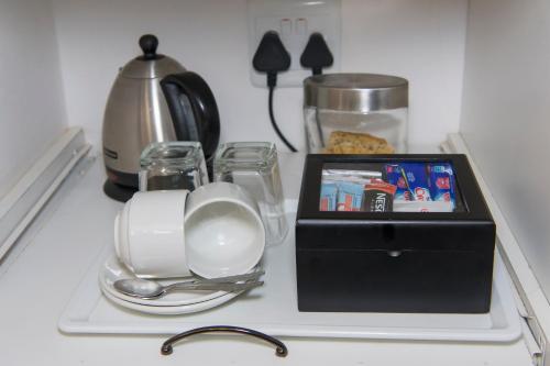 a tray with a tea set and a box on a counter at Bayswater Lodge in Bloemfontein