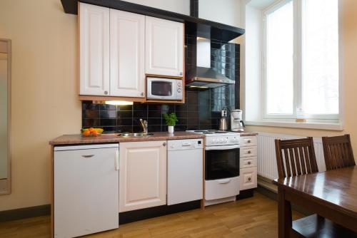 a kitchen with white cabinets and a sink and a table at Hotelli Ville in Tampere
