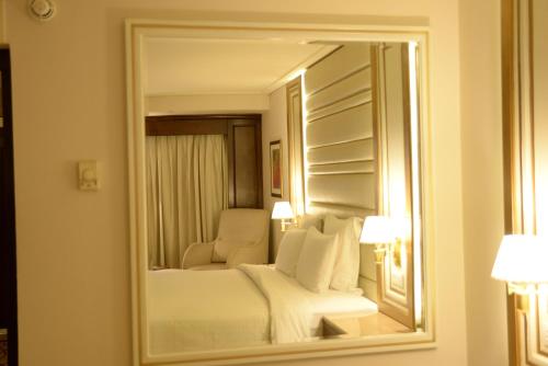 a mirror in a hotel room with a bed and a chair at Pearl Continental Hotel, Karachi in Karachi