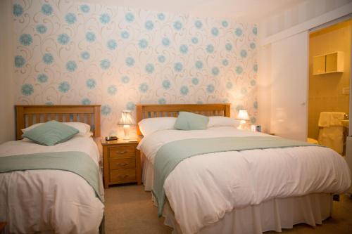 two beds in a small room with wallpaper at Weir Mill Farm in Cullompton