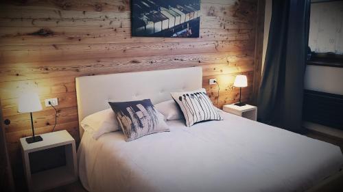 a bedroom with a white bed with two pillows at Aqua Apartments Spa Housemuhlbach in Sappada