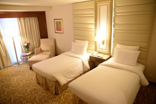 a hotel room with two beds and a chair at Pearl Continental Hotel, Karachi in Karachi