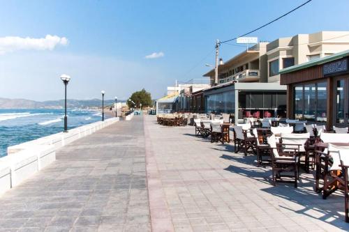 a sidewalk with tables and chairs and the ocean at Rena House in Kissamos