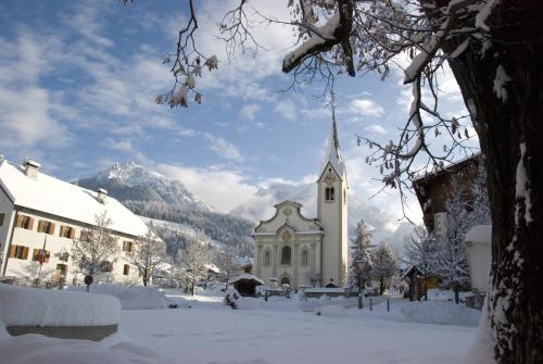 a small church in the snow with mountains in the background at Casa Teresa Martin in San Vigilio Di Marebbe