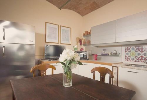 a kitchen with a table with a vase of flowers on it at Villa il Pino by VacaVilla in Lari