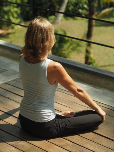 a woman sitting in a yoga pose on a deck at KAJU GREEN eco lodges in Unawatuna