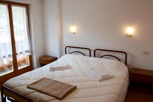a bedroom with a bed with white sheets and a window at Casa Teresa Martin in San Vigilio Di Marebbe