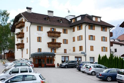 a large white building with cars parked in a parking lot at Casa Teresa Martin in San Vigilio Di Marebbe