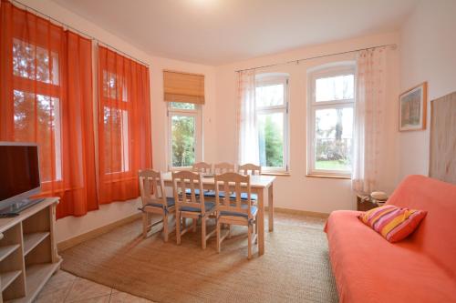 uma sala de estar com uma mesa, cadeiras e janelas em Apartamenty Rybak 3 em Niechorze