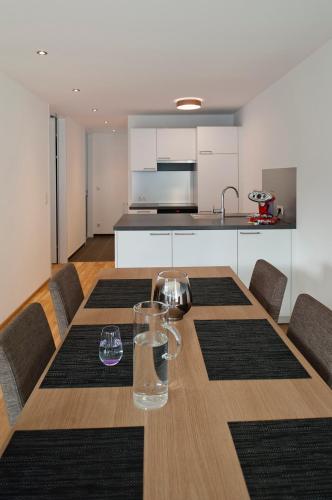 a dining room table with chairs and a kitchen at Relaxed Urban Living - Aparthotel und Boardinghouse in Dornbirn