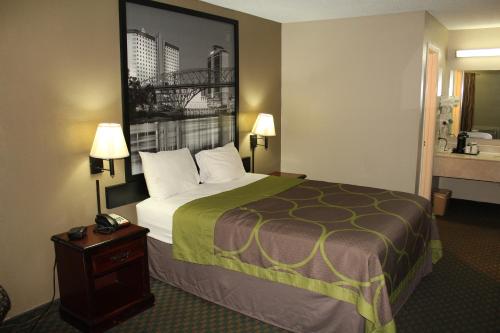 a hotel room with a large bed and a telephone at Super 8 by Wyndham Bossier City/Shreveport Area in Bossier City