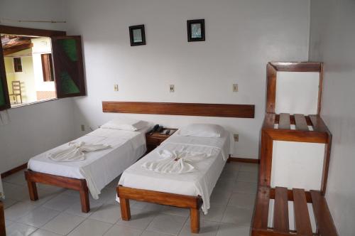 a room with two beds and a mirror at Pousada Do Bosque in Itajuípe