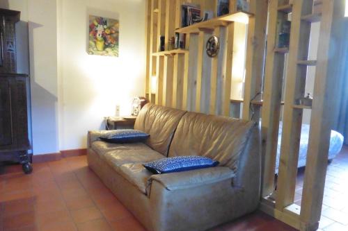 a leather couch in a living room with two blue pillows at La Loge in Sanssac-lʼÉglise