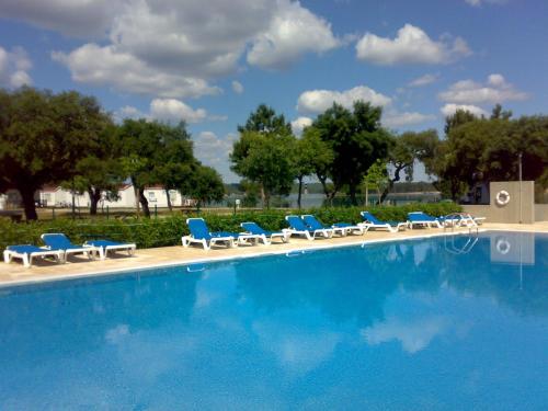 uma piscina com espreguiçadeiras e um monte em Parque de Campismo Orbitur Montargil em Montargil