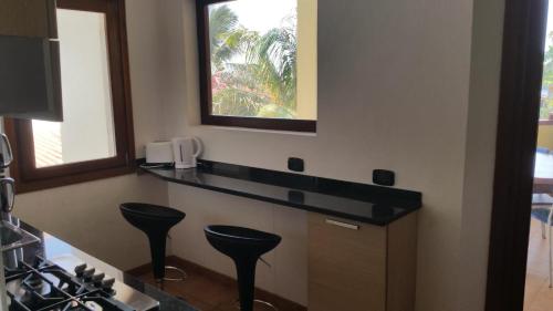 a kitchen with black counter stools and a window at Porto Antigo Three Bed Apartment with Sea View in Santa Maria