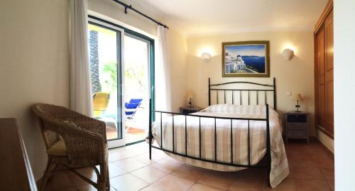 a bedroom with a bed and a sliding glass door at Vila Castelo Tradicional in Ferragudo