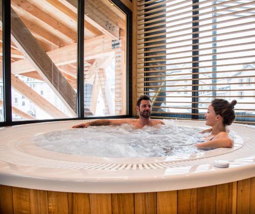a man and a woman in a hot tub at Alpina Eclectic Hotel in Chamonix