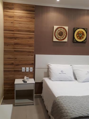 a hotel room with two beds and a table at Hotel Loureiro in Rio Branco