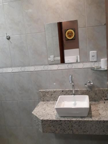 a bathroom with a sink and a clock on the wall at Hotel Loureiro in Rio Branco