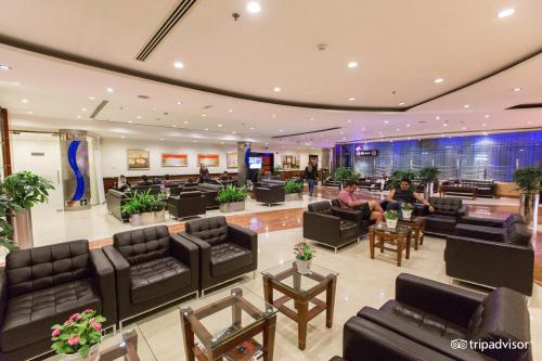 a lobby with couches and tables and people sitting at Grand Central Hotel in Dubai