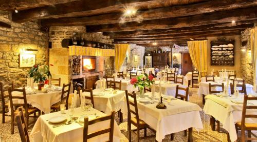 a restaurant with white tables and chairs with flowers on them at Logis Auberge La Diege in Capdenac-Gare