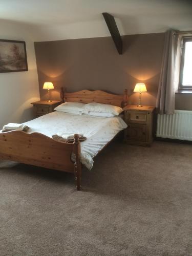 a bedroom with a wooden bed and two night stands at Stone Cottage in Ponteland