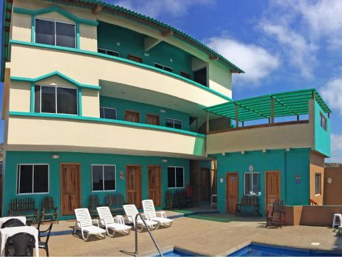 a building with chairs and a pool in front of it at The Lookout Beach Hotel in San Lorenzo