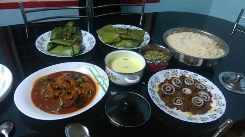 a table topped with bowls of food and rice at Punerjeni Homes in Alleppey